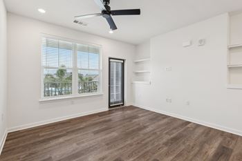 A room with a ceiling fan and a window overlooking a balcony.